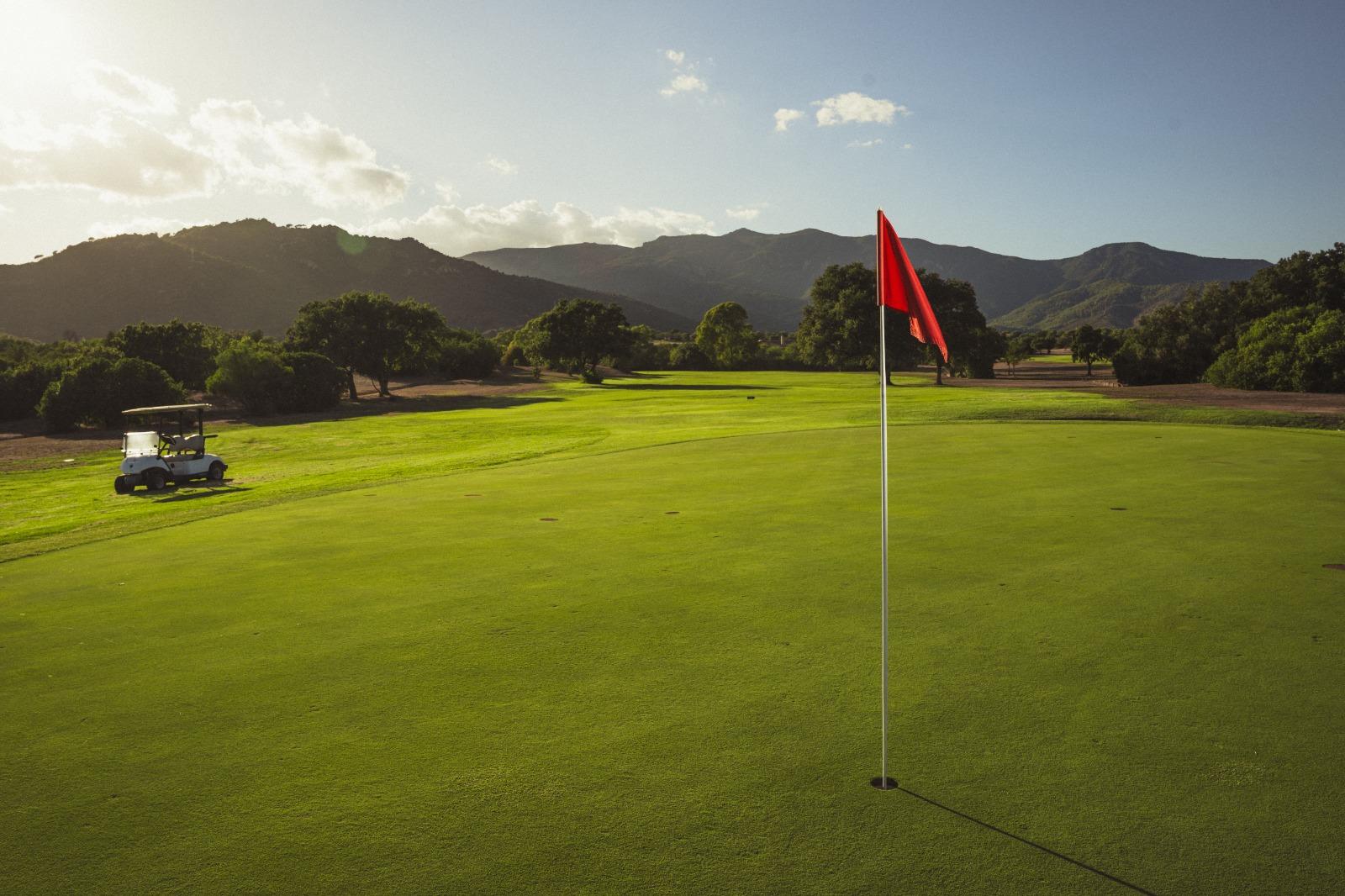 Is Molas Golf Club, green and flag with the Sardinian hills behind at golden hour