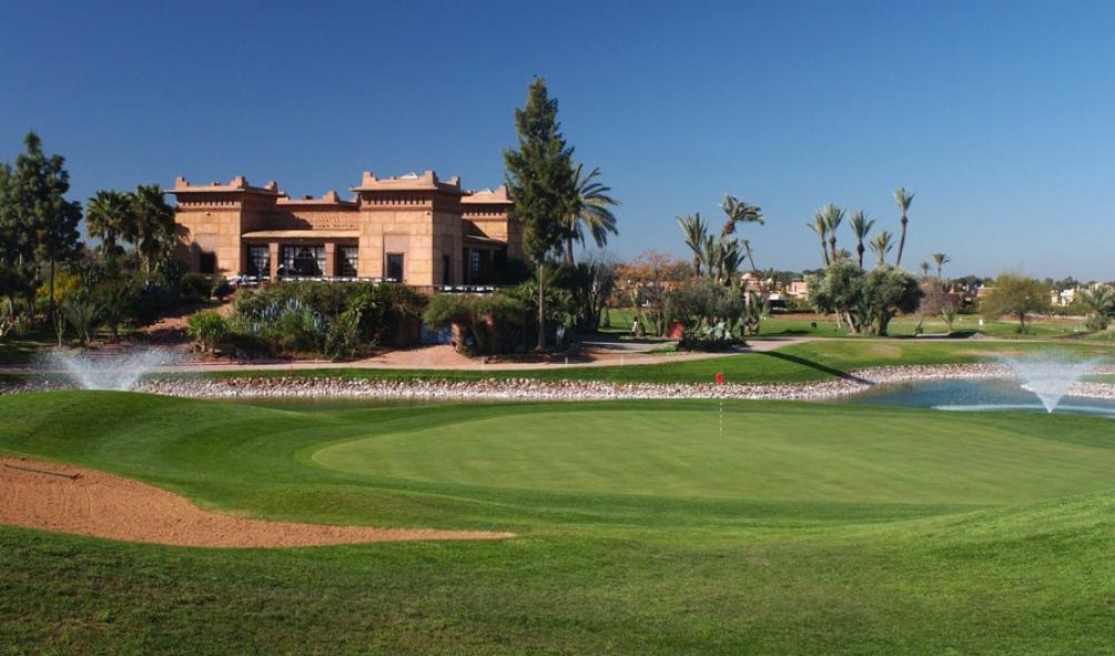 Amelkis Golf Club, desert fairway and palms below the snow capped Atlas Mountains near Marrakech, Morocco